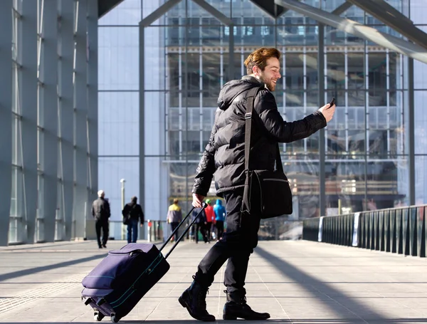 Man walking with suitcase and looking at mobile phone