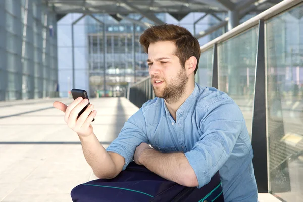 Man looking at mobile phone with confused expression