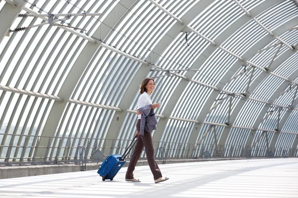 Smiling business woman walking with bag at station