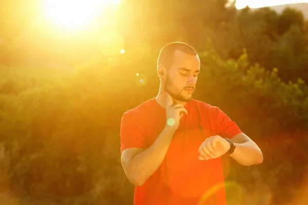 Sports man checking pulse and looking at watch