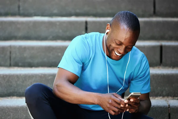 Smiling man looking at mobile phone and listening to music