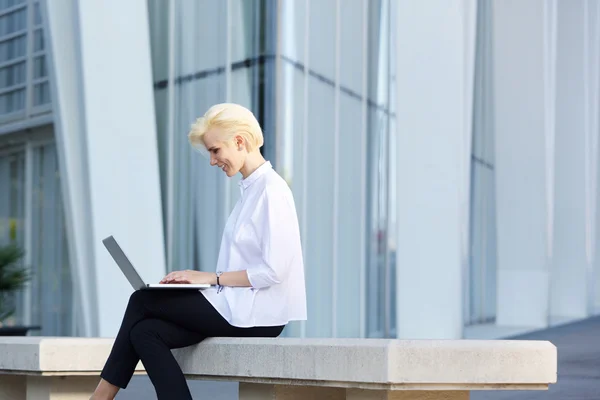 Young modern business woman smiling with laptop outside