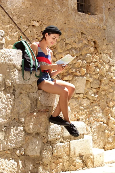 Young travel woman sitting outside reading map