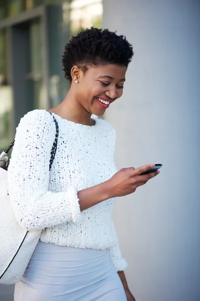 Woman walking and looking at mobile phone outside