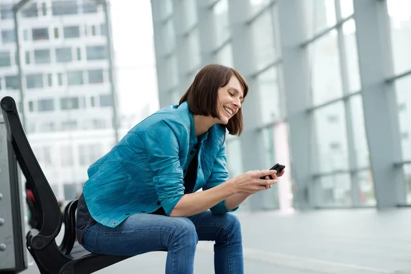 Smiling older woman sitting with mobile phone