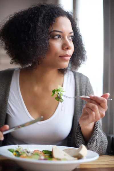 Beautiful young  woman eating salad at restaurant