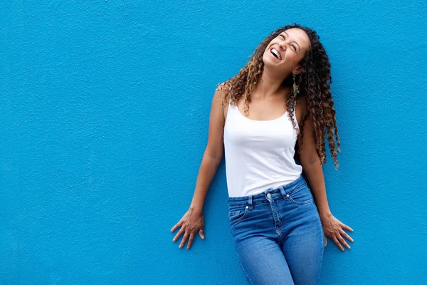 Cheerful young woman standing against blue wall