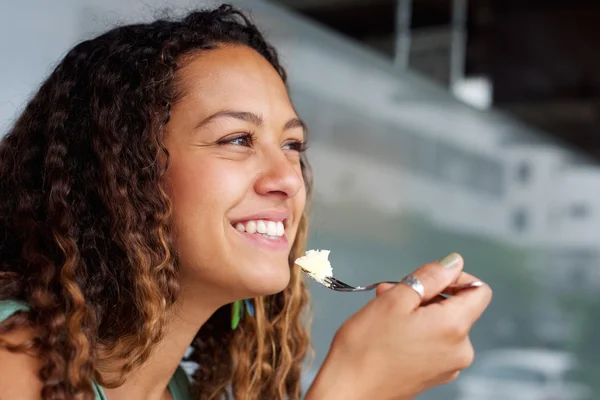 Happy young woman eating cheese cake