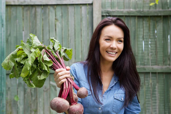 Smiling vegetarian woman holding bunch of beetroots