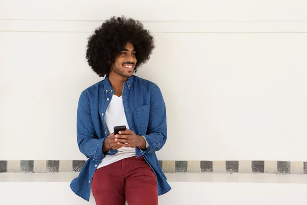 Smiling young black man using cellphone