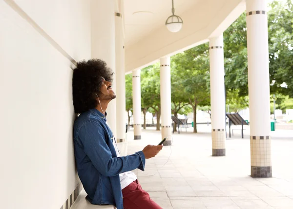 Modern man smiling with mobile phone ad earphones