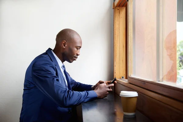 Black businessman in a cafe using cell phone