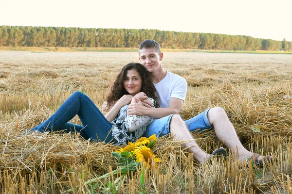 Happy young couple sit in wheaten field at evening, romantic people concept, beautiful landscape, summer season