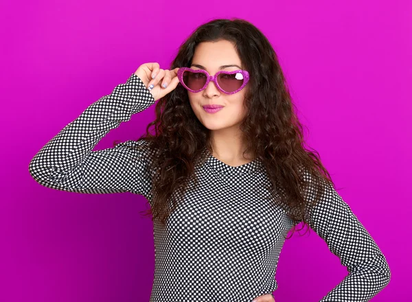 Young woman beautiful portrait, posing on purple background, long curly hair, sunglasses in heart shape, glamour concept