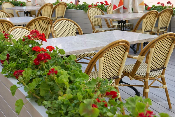 Street cafe interior in city, tables and chairs, ornate with flowers, summer season, without people, touristic place