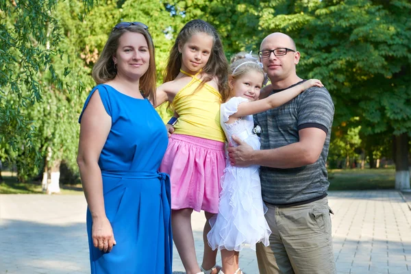 Happy family portrait on outdoor, group of four people posing in park, summer season, child and parent