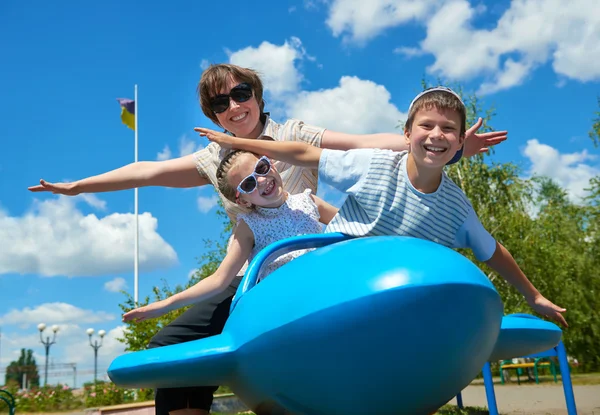 Child and woman fly on blue airplane attraction in park, happy family having fun, summer vacation concept