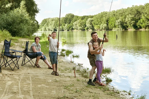 People camping and fishing, family active in nature, child caught fish on bait, river and forest, summer season