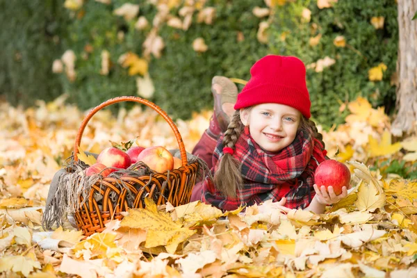 Little girl in autumn park with apple basket