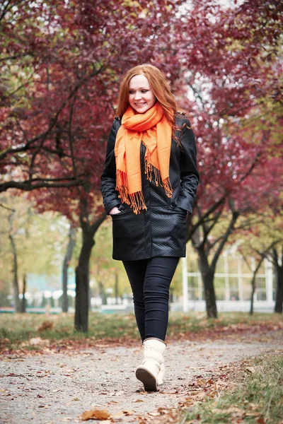 Redhead girl walk on pathway in city park, fall season