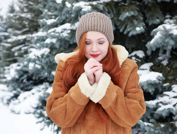 Young woman warms hands at winter outdoor