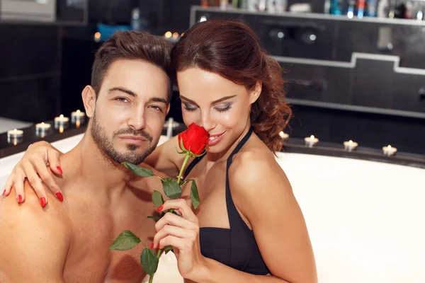 Sensual couple with rose in jacuzzi honeymoon