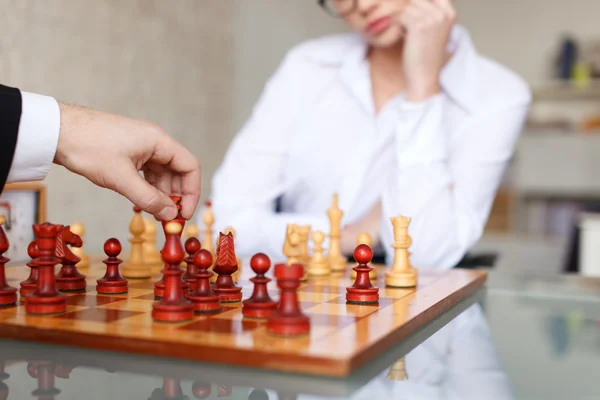 Man and woman playing chess in office
