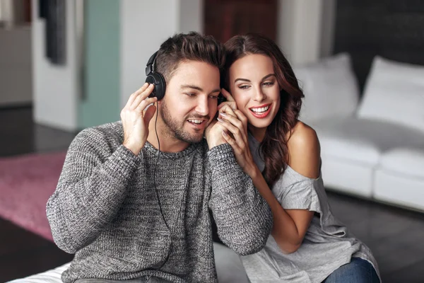 Happy young couple listening music at home on headphones