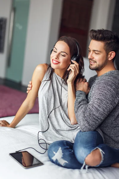 Young couple listening music by headphones indoors