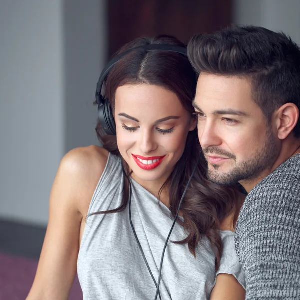 Young happy couple listening music on headphones