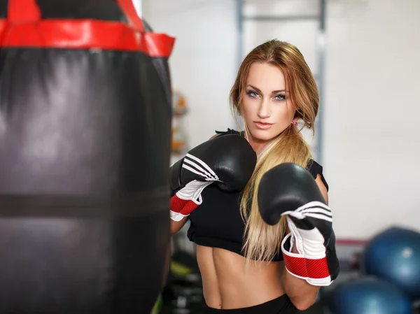Woman fighter with heavy bag in gym