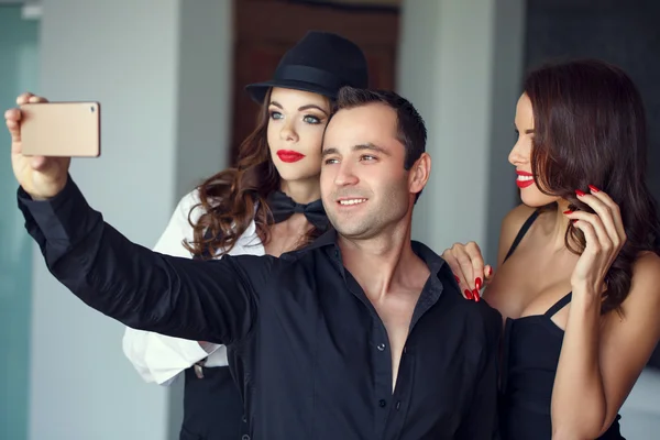 Successful young macho man taking selfie with women