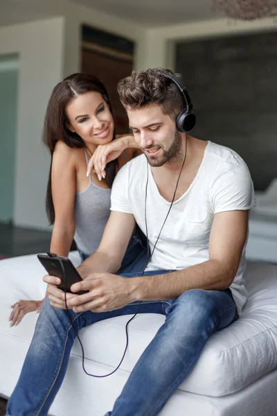 Man listening music indoor by headphones at home with grilfriend