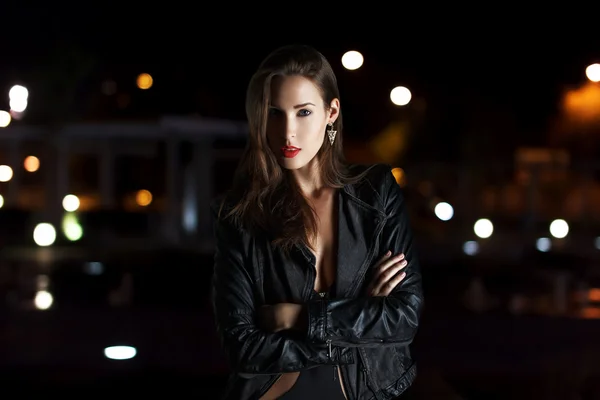Fashionable woman in leather jacket posing outdoor at night