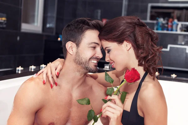 Happy young couple with rose in jacuzzi