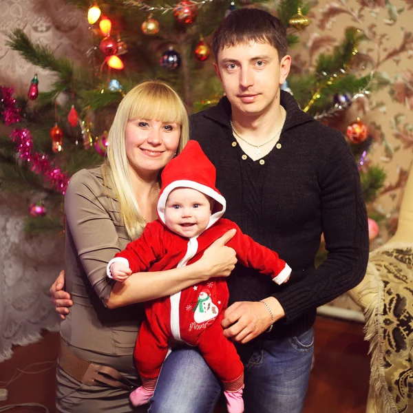 Happy young family with Christmas baby near the Christmas tree