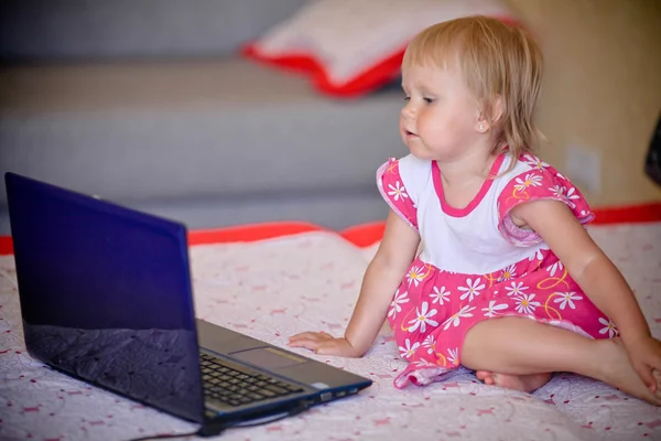 The little girl watches animated cartoons on the laptop