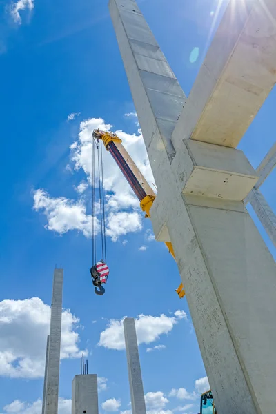 Mobile crane is assembly skeleton of huge hall. Long concrete pi