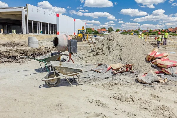 Cement mixer machine and wheelbarrow at building site