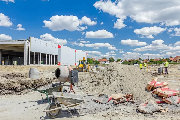 Cement mixer machine and wheelbarrow at building site