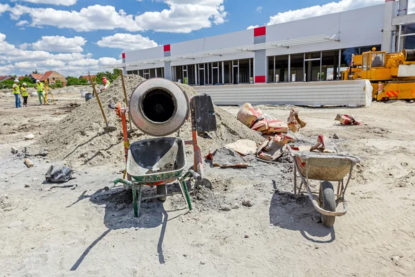 Cement mixer machine and wheelbarrow at building site