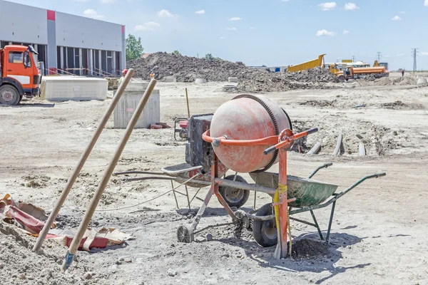 Cement mixer machine and wheelbarrow at building site