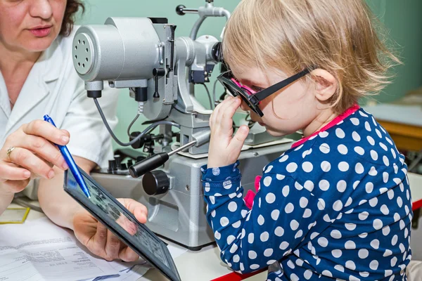 Child is at eye examination in clinic with special equipment.