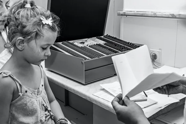 Eye exam, cute little girl is reviewing eyesight.