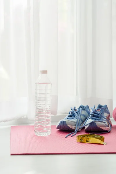 Sport shoes, yoga mat, bottle of water and centimeter on wooden