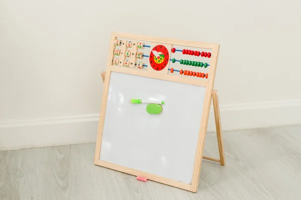 Easel isolated on grey wooden floor and white wall.