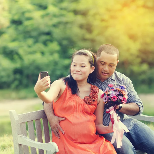 Selfie Asian Couple Expecting Pregnancy sitting on bench in the