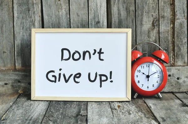 Don't give up message note on white board with red retro clock o