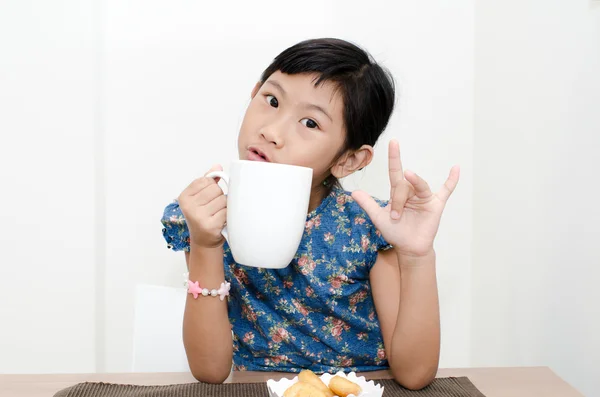 Asian girl holding a cup of milk during breakfast at home.