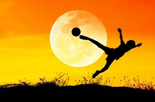 Silhouette of soccer man playing with the ball and big moon.
